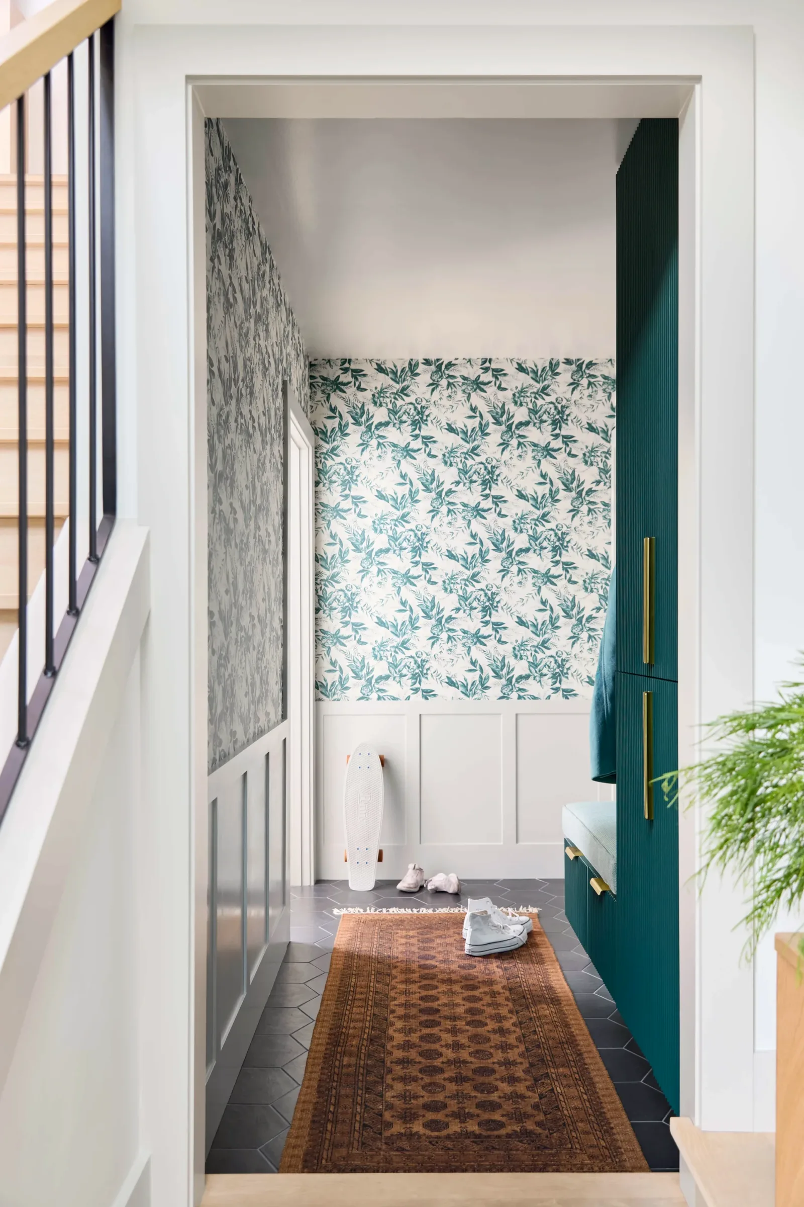 Hallway opening into a powder room papered in a green botanical print