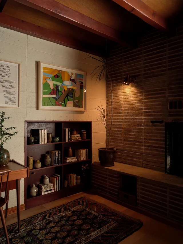 Living room with exposed beams, brick chimney, and built-in shelving