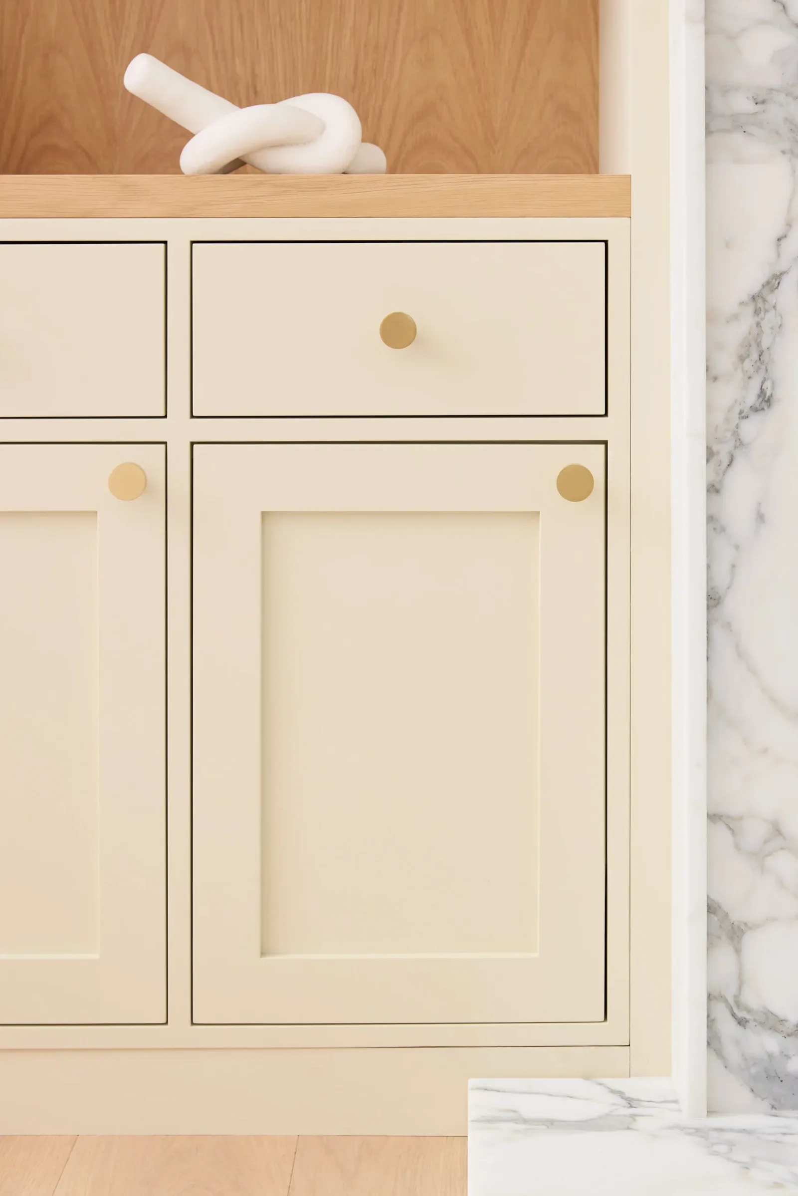 Painted inset cabinet door and drawer with brass knobs against marble