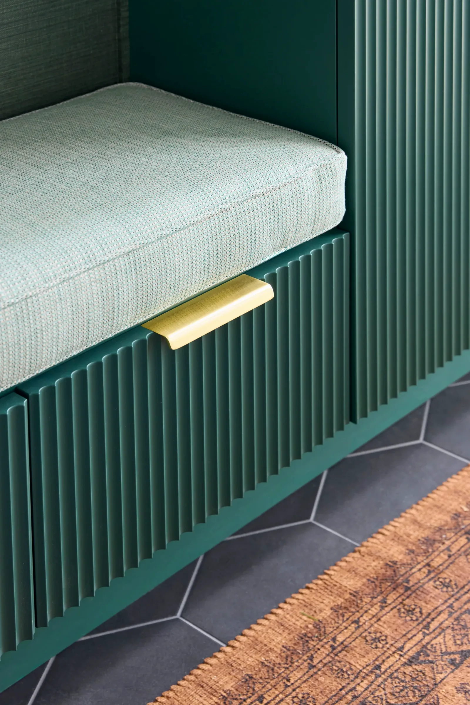 Fluted casework detail at the mudroom bench, brass pull and cushion edge