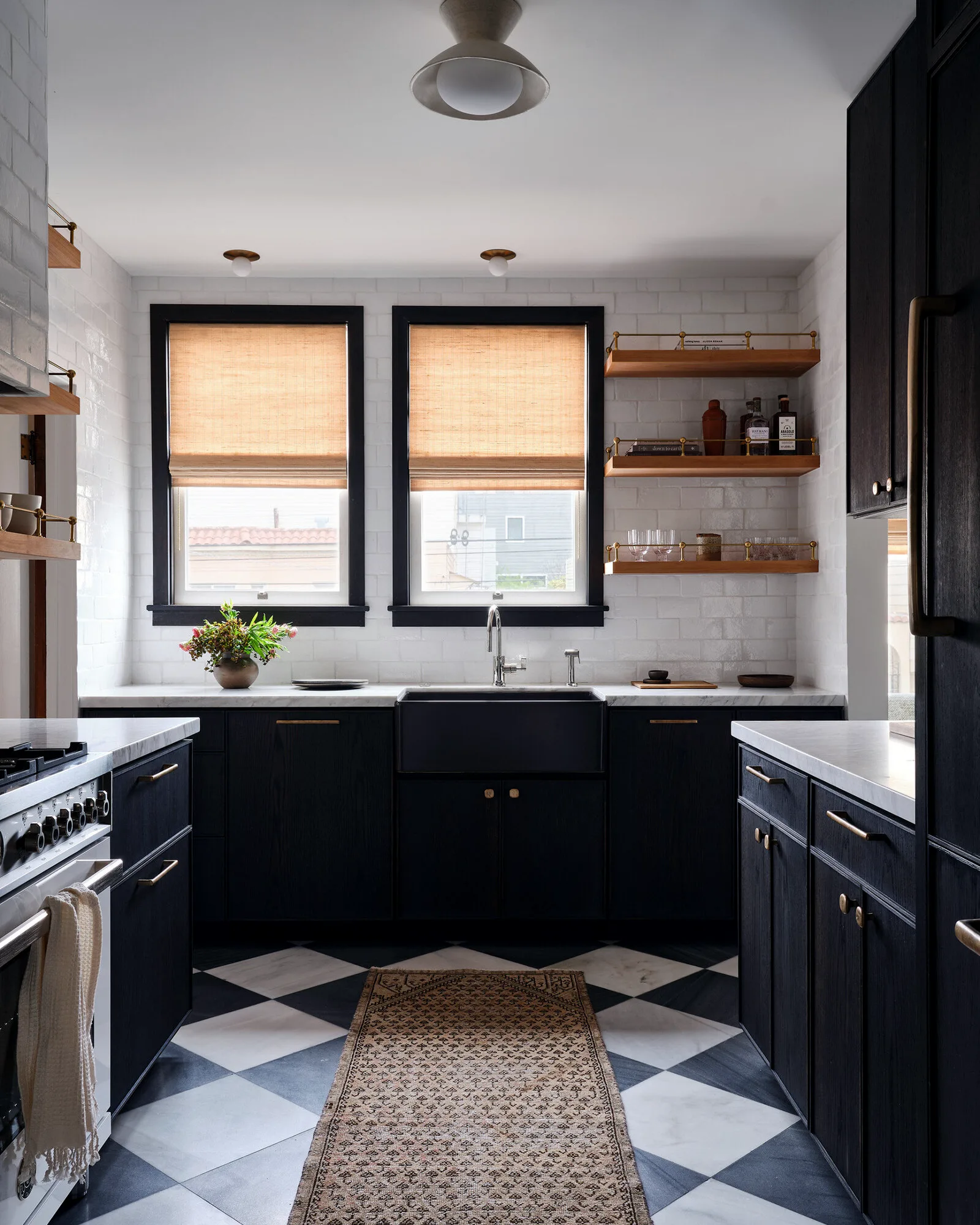 Dark inset kitchen cabinetry with open walnut shelving and a checkerboard floor
