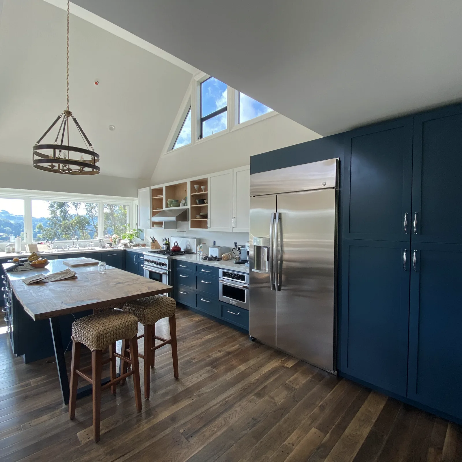 Vaulted kitchen with deep blue cabinetry, a wood island, and clerestory windows