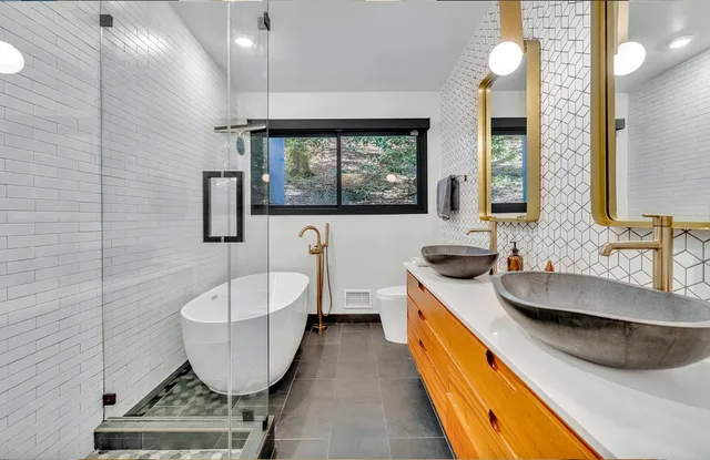 Bath with a freestanding tub, wood vanity, and vessel basins