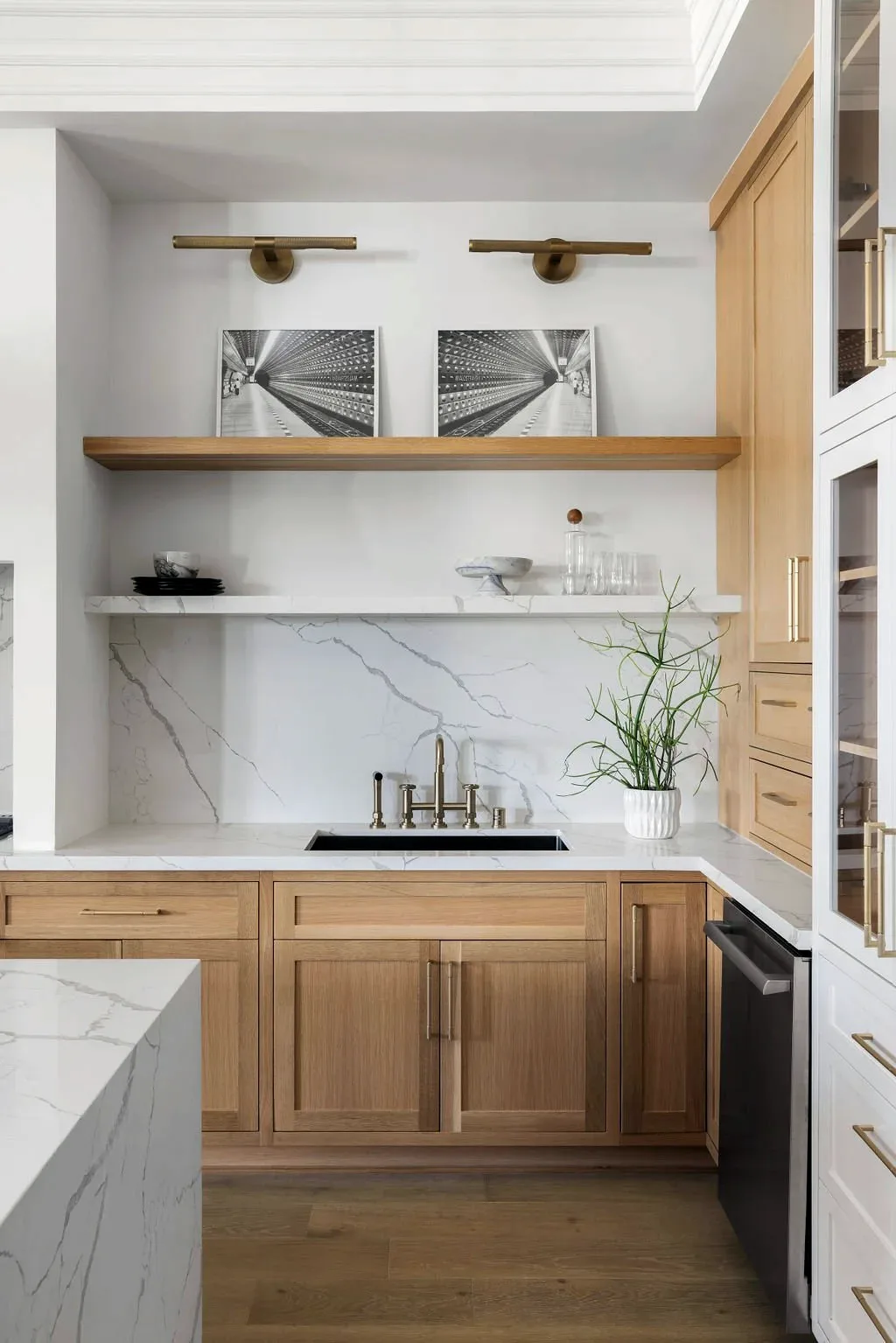 Oak cabinetry and open shelving beside a marble counter run