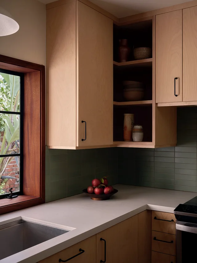 Kitchen corner with maple uppers, open shelving, and a green tile backsplash