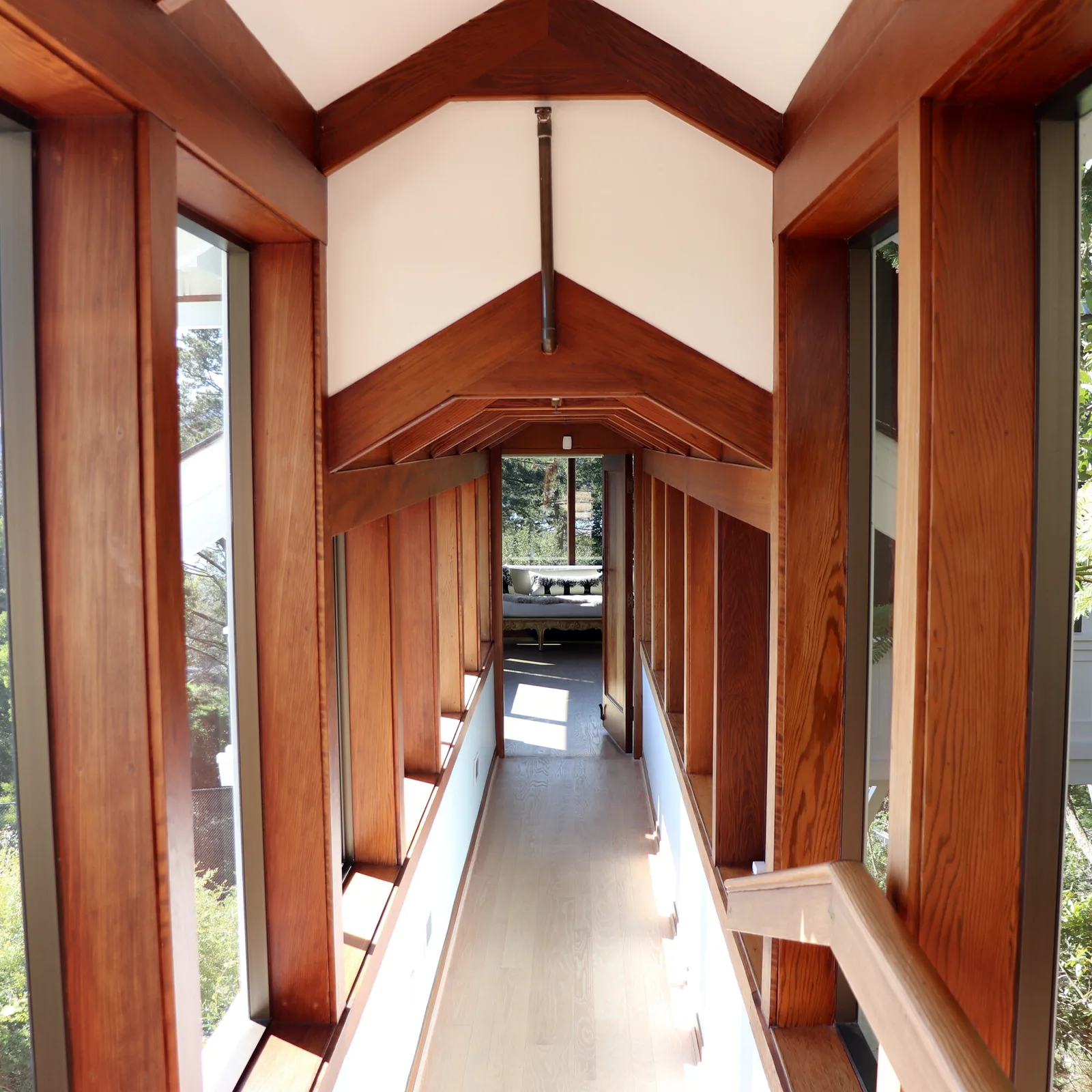 Timber-framed glazed breezeway connecting two parts of a hillside house