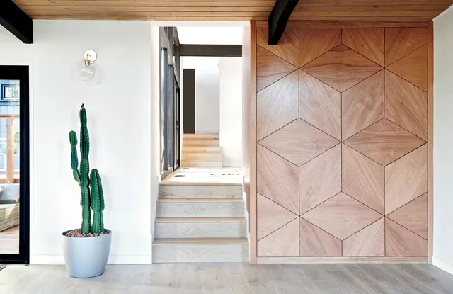 Hall with a geometric wood-panelled wall leading to the stair