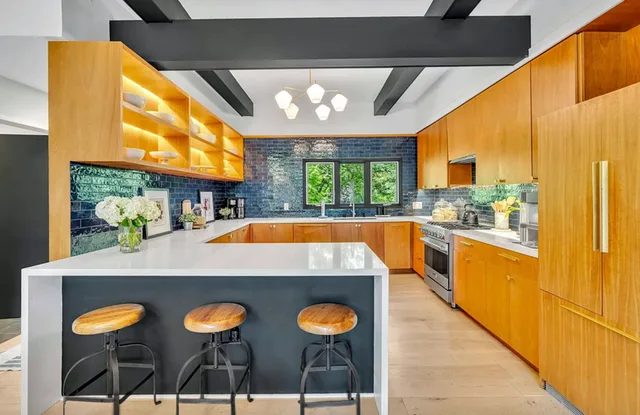 Kitchen with warm wood cabinetry, a dark island, and blackened beams